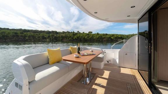 A stylish aft lounge with yellow cushions and wine setup on the Leeloo yacht.