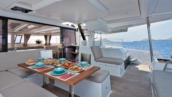 Helidoni charter catamaran features a large dining table with panoramic sea views.