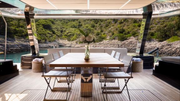 Aft deck dining space on Amber One with green coastal views near Kastela.