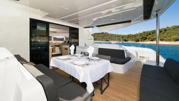 На кормовой палубе катамарана в Кастеле — стол под навесом и мягкие диваны для комфортной трапезы.