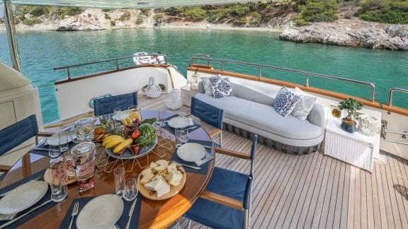 Anchored in an Athens bay the 4 cabin 10 guest Estia Poseidon motor yacht offers an aft deck dining table and seating ar