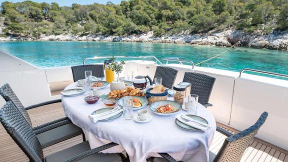 On the aft deck of Wish Alfamarine 91, a breakfast table is set with a sea and bay view.