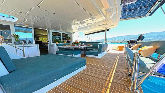 The aft deck of Ace of Hearts in Athens features a seating area, dining table and open sea view.