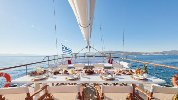 The aft deck of White Pearl gulet in Athens features a long dining table with open sea views.