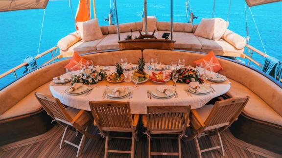 Ein elegant gedeckter Tisch auf dem Deck eines Segelschiffs, bereit für ein luxuriöses Dinner mit Meeresblick.