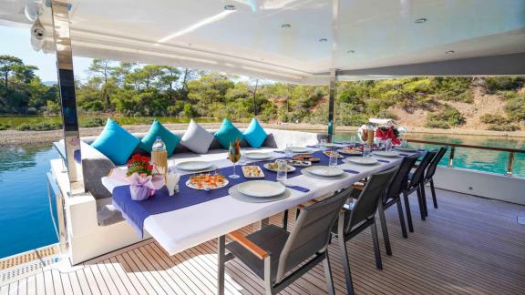 Auf dem Deck der Yacht Çınar Yıldızı befindet sich ein elegant vorbereiteter Essbereich im Freien, gefüllt mit Essen und