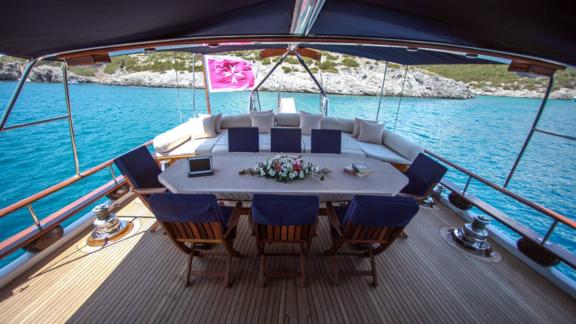 An inviting dining area on the deck of the gulet Dulcinea, anchored in a picturesque bay.