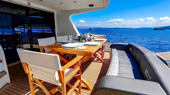 The aft deck of motor yacht Zeus 1 offers an ideal table and comfortable seating for outdoor dining.