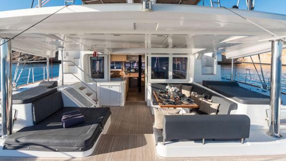 Outdoor area of the yacht with comfortable seating and a set dining table.