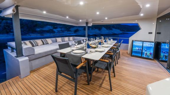Elegant dinner setup on the aft deck of the yacht with a sea view. The table is set with white linens and stylish servic