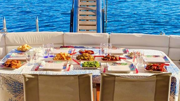 The aft deck of motor yacht Sweet Lily features a dining table with a sea view.