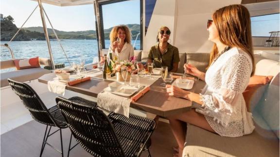 Guests enjoy a cozy meal with a sea view on board the catamaran Bali 4.2 in Fethiye, Turkey.