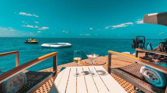 Zwei Gläser Wein auf dem Wasserdeck des Katamaran Samara, mit Blick auf das klare, blaue Meer und Wassersportgeräte.