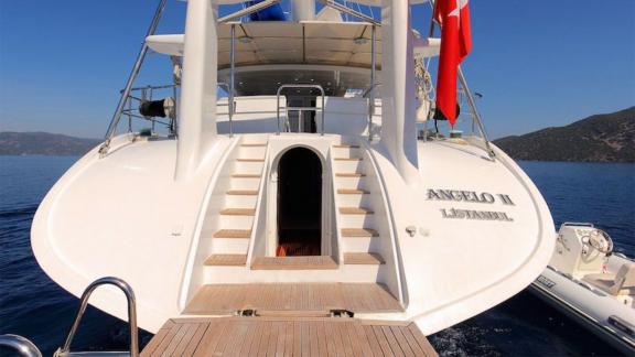 Angelo 2 motorsailer anchored in a peaceful bay with entrance steps on the aft deck.