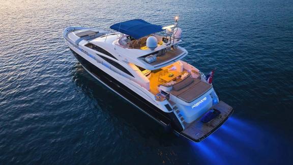 The motor yacht Agave is illuminated at sunset, cruising on calm waters.