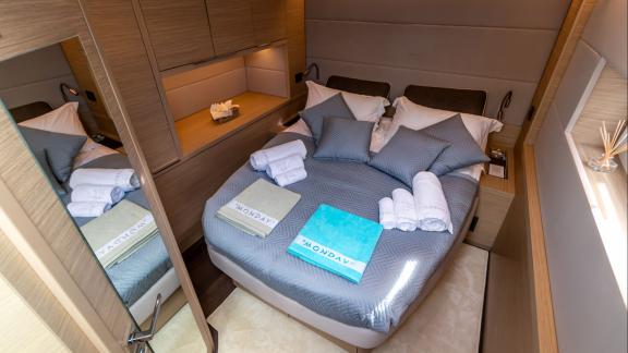 Agenda 55 catamaran features a modern double cabin with elegant wooden interiors and comfortable bedding onboard.