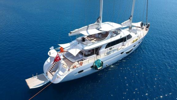 Motorsailer Angelo 3 on blue waters, captured from above, featuring a spacious and comfortable deck.