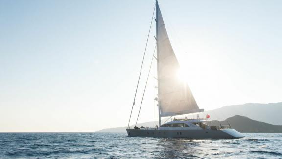 Моторный парусник All About U 2 плывет в открытом море на закате.