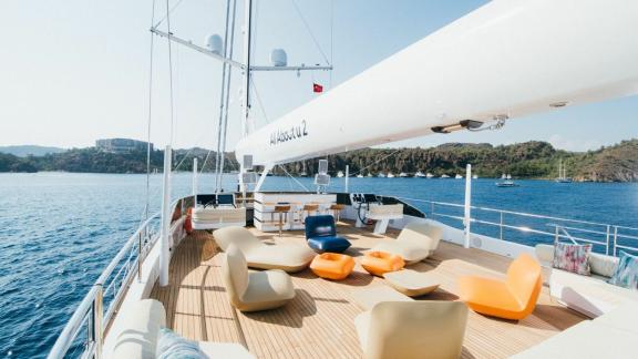 Стильная зона отдыха на палубе моторного парусника All About U 2 с видом на море.