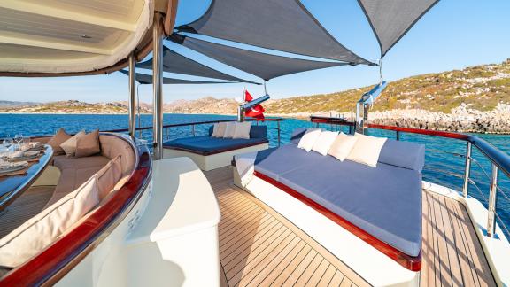 In Göcek gulet charter option Always Smile aft deck with shaded lounge beds and sea view visible.