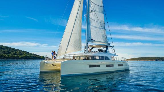 The Catamaran Amada Mia sails peacefully along the Adriatic coast of Croatia, while two people enjoy the view of the cle