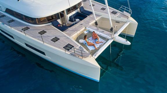 Guests enjoying the sun on the net of the luxurious catamaran Amada Mia in the calm waters of Croatia