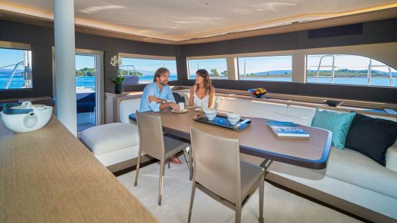 Modern dining area in the salon of the catamaran Amada Mia with large windows and a cozy atmosphere