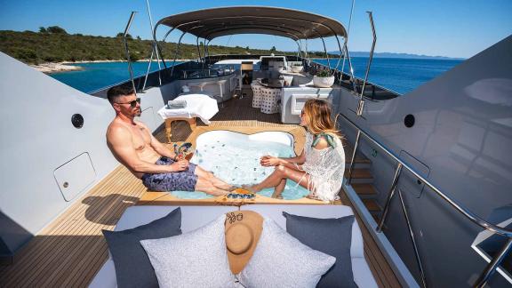 A couple relaxing in the jacuzzi on the upper deck of the motor yacht Anavi.