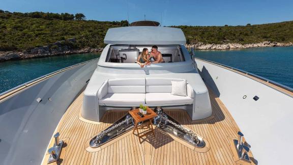 The foredeck of the motor yacht Anavi features a stylish seating area with a couple in a romantic setting.