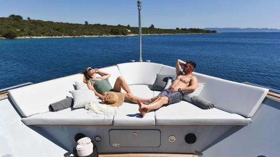 A couple relaxing in the sunbathing area on the foredeck of the motor yacht Anavi.