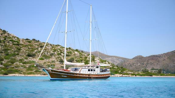 Beautiful gulet in turquoise waters, surrounded by green hills, perfect for peaceful sailing trips.