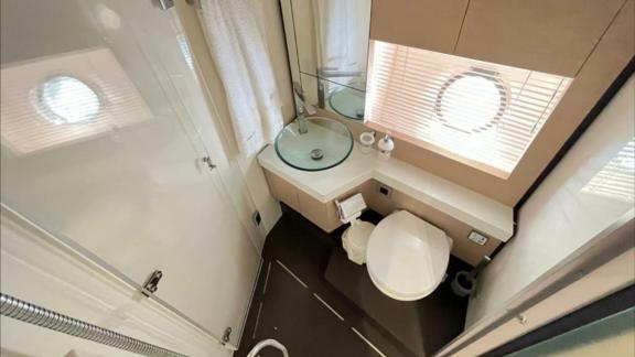 Among Saint Tropez yacht charter options Escapade motor yacht shows bathroom with shower sink and toilet.