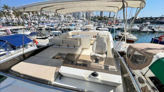 Among Saint Tropez yacht charter options Escapade motor yacht shows upper deck with seating and helm station.