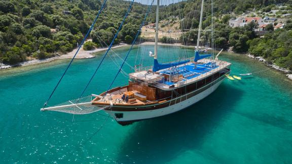 Eine 9-Kabinen-Gulet aus Split, vor Anker in einer malerischen Bucht mit türkisfarbenem Wasser.