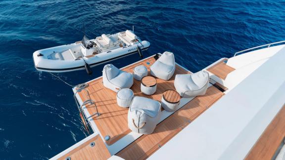 Motor yacht Nemesis offers comfortable seating on the platform with tender boat near Mallorca.