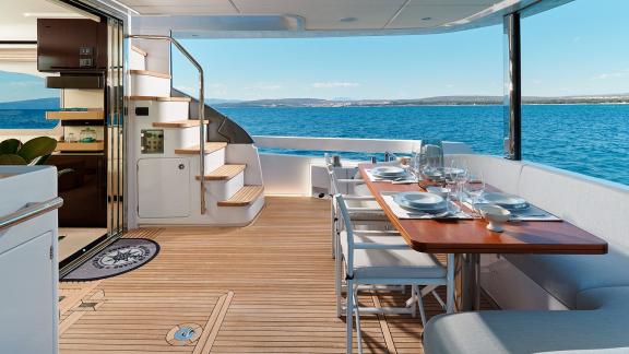 Auf dem Achterdeck stehen Holztisch, Stühle und Sofa mit Blick auf das Meer.