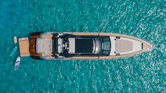 The Jungle motor yacht is anchored in Ibiza, showcasing spacious decks and paddle boards from above.