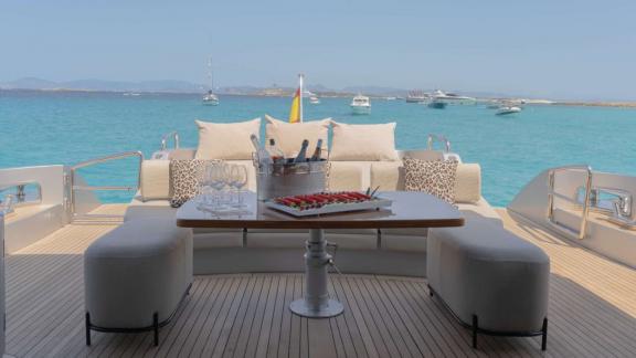 The Jungle motor yacht is anchored in Ibiza, featuring an aft deck dining table and lounge seating.