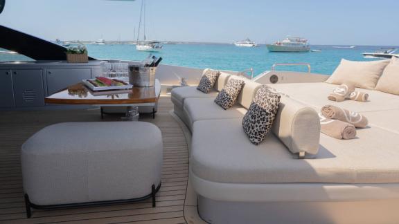 The Jungle motor yacht is anchored in Ibiza, featuring spacious sunbeds and lounge seating on deck.