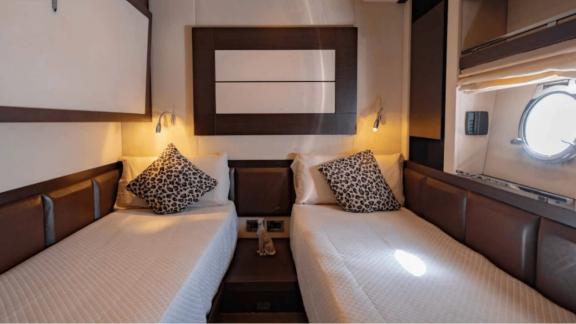 The guest cabin of The Jungle in Ibiza features twin beds and a round porthole window.