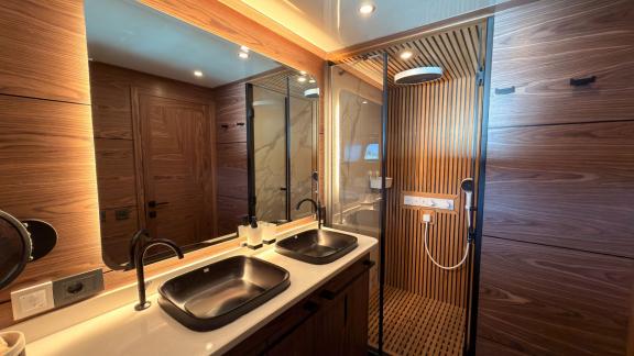 Аренда люкс гулета Oguz Marin в Бодруме предлагает стильную ванную с двойной черной раковиной и отделкой из дерева для к