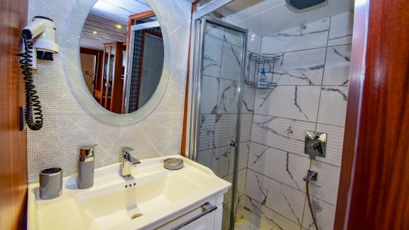 A modern bathroom on the gulet 'Ugur' with a shower and round mirror.