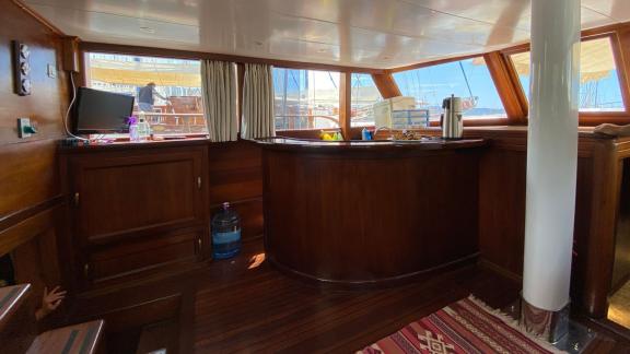 Интерьер гулета Be Happy в гавани, оборудованный уютным баром и большими окнами.