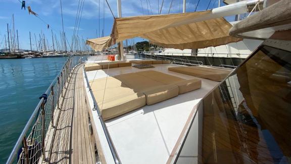 Просторная солнечная палуба гулета Be Happy в гавани с удобными лежаками и навесом.