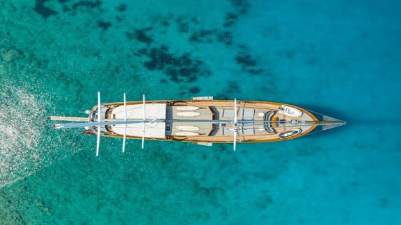 Die Gulet Bedia Sultan in Bodrum aus der Vogelperspektive, umgeben von klarem, türkisfarbenem Wasser.