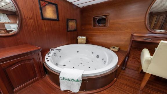 Ein Jacuzzi in einem Holzinterieur auf einem Boot, daneben ein Schreibtisch und ein Spiegel.