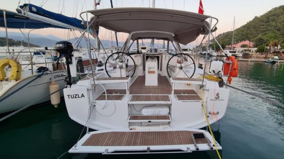 The aft deck of Triton 89 sailing yacht docked at the pier, positioned alongside other boats.