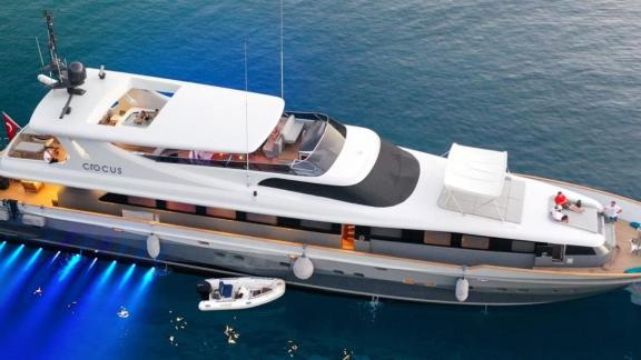 Роскошная яхта движется во всем своем великолепии и с включенными огнями посреди моря.