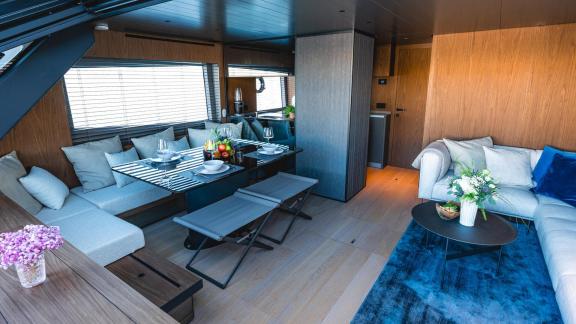 Motor yacht Kimani Bluegame BG74 features a modern wood‑toned interior with a comfortable lounge and dining space.