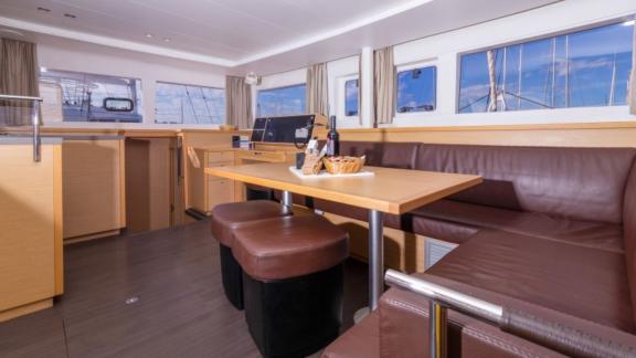 Cozy salon area of the Saelma Lagoon 450 with brown leather sofas and a wooden dining table.